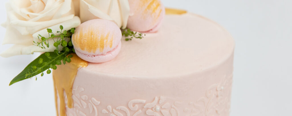 Cakes by Yours Truly design pink embossed frosting with flowers and macarons on top